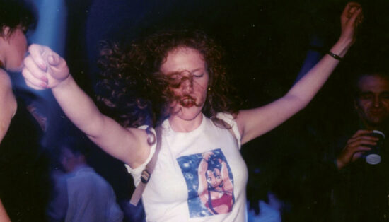 Jeune fille aux cheveux bouclés portant un tee-shirt manga qui danse dans la greenroom aux Trans Musicales 1995 lors d'une soirée Planète